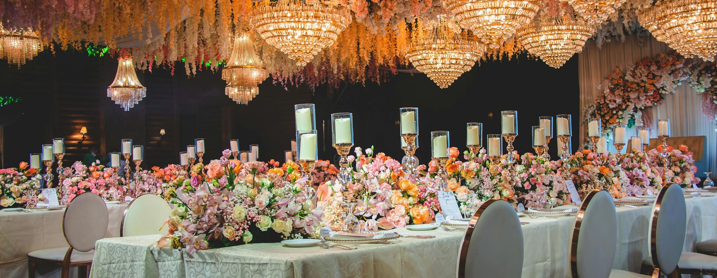 an image of a hall with chandeliers on the top illuminating yellow lights 