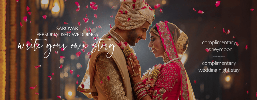Newly wed couple embracing each other in a decorated area and flower petals are falling on them. The background in the banner says write your own story as sarovar promised personalised wedding, free wedding night stay, and honeymoon.