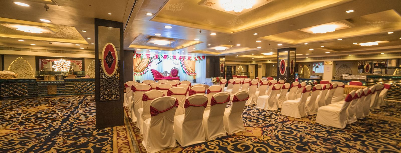 Maurya featuring rows of chairs facing a stage with patterned flooring and ambient lightning.