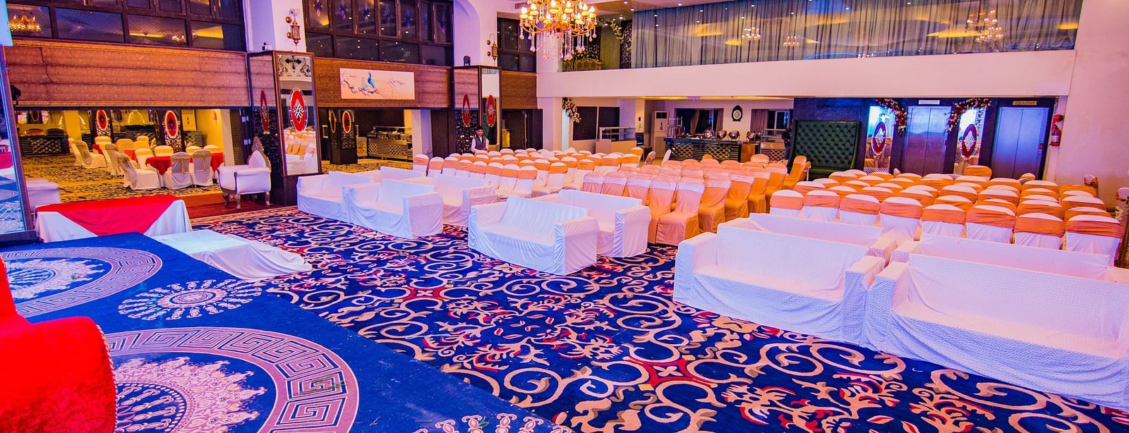Kohinoor showcasing rows of chairs facing the stage with patterned flooring and ambient lighting.
