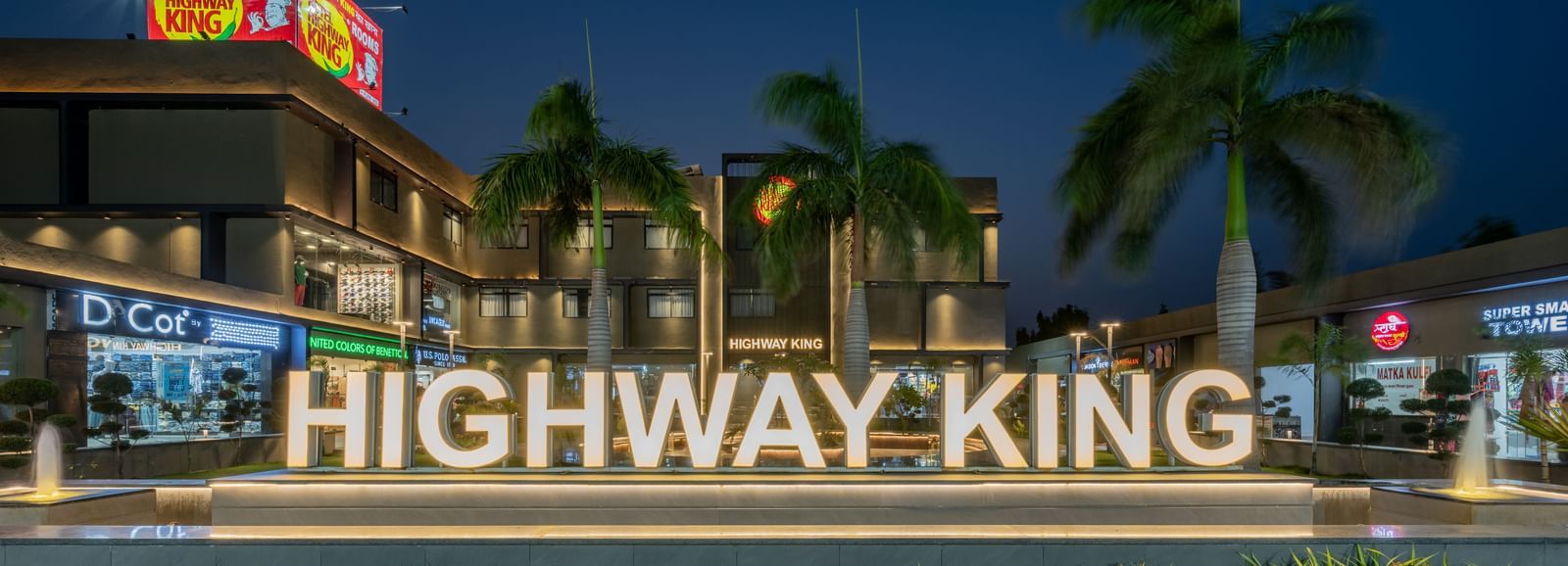 A signage in front of the Hotel Highway King in Behror, with the words 'Highway King' written out on an elevated platform.