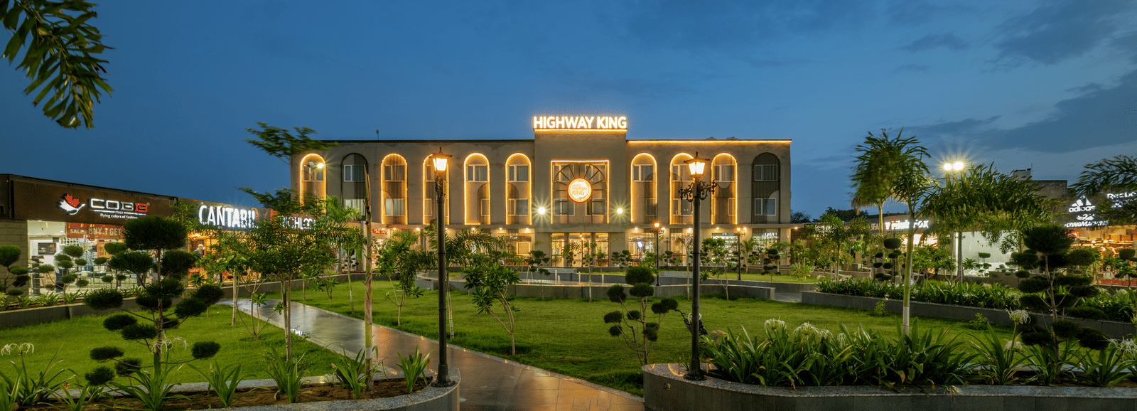Facade view of Hotel Highway King, Neemrana, nestled amidst lush plants surrounding the building.