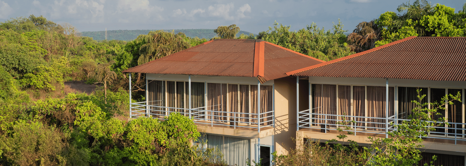 An aerial view of our accommodation buildings with orange-tiled balconies, surrounded by lush greenery - Perfectstayz Koko Maya