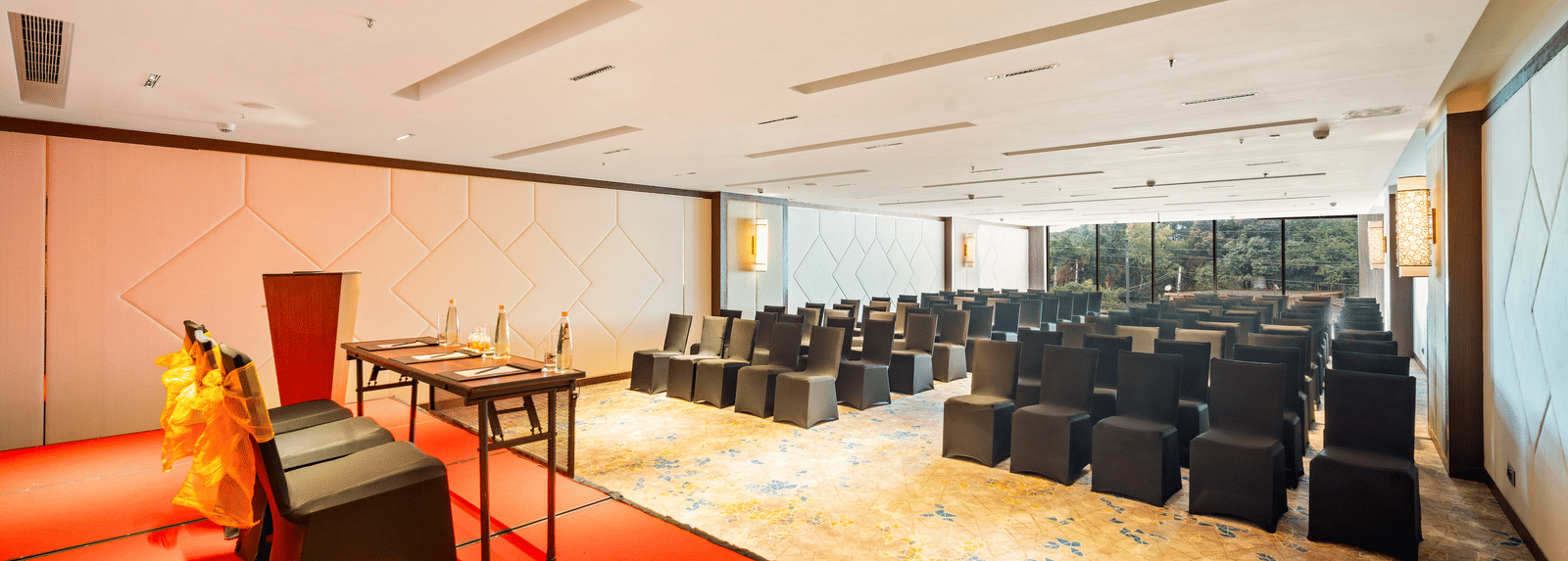 An image of Godavari conference hall with black chairs facing the podium at Grand Vijayawada by GRT Hotels.