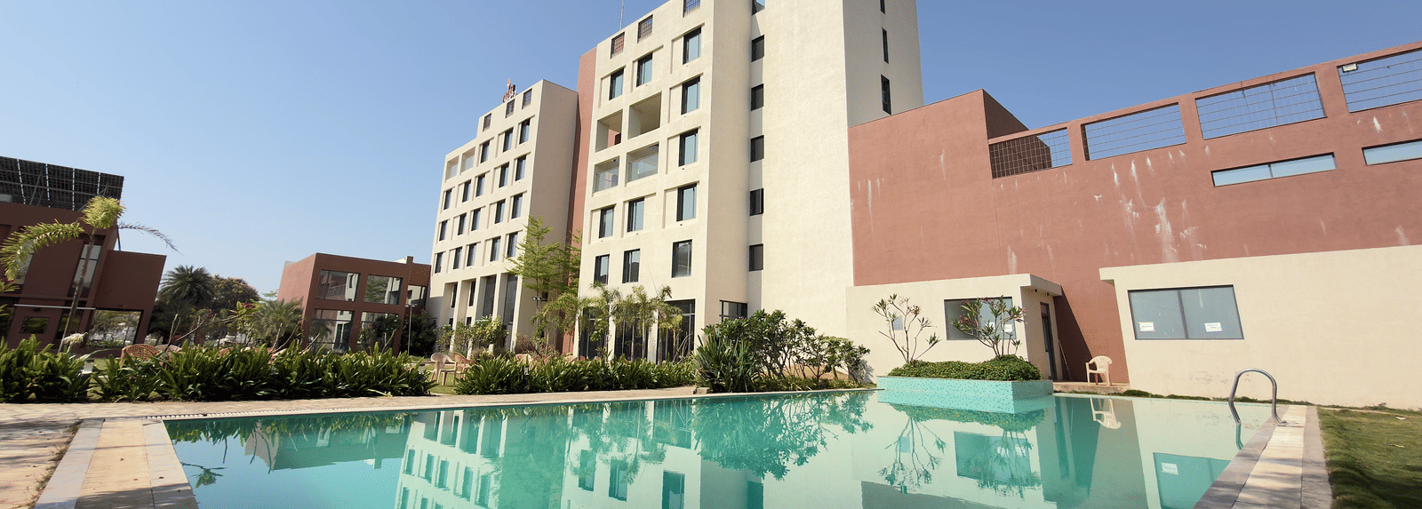 Vinti Resort building with a swimming pool and trees in the foreground.