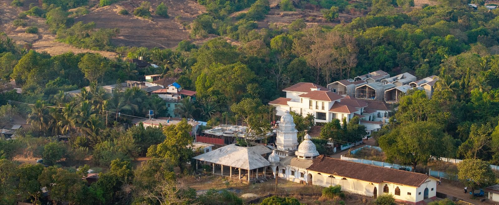 A panoramic view of a valley with rolling hills, scattered houses, and vibrant greenery under a clear sky - BluSalzz Villas - Alocassia, Anjuna