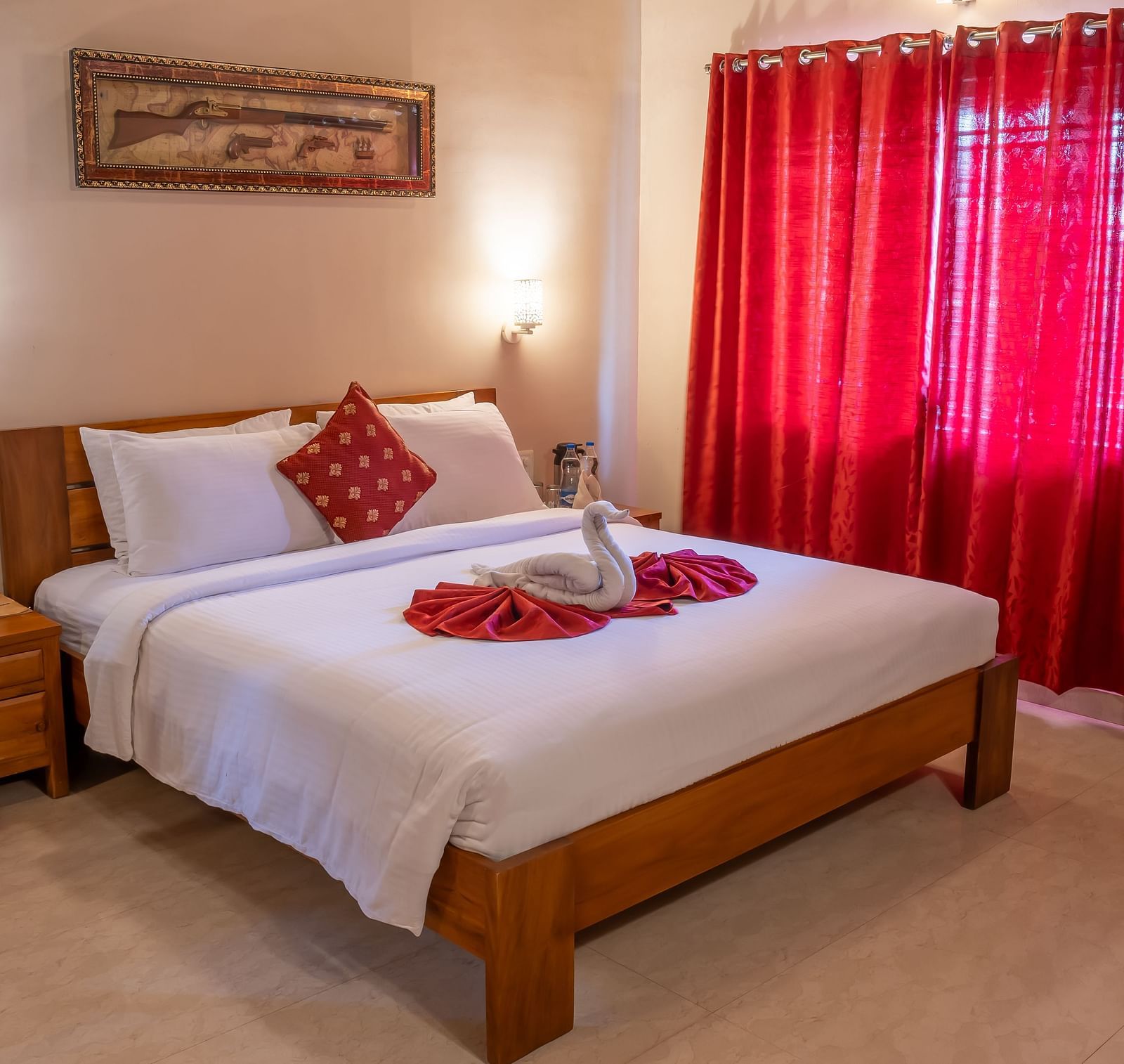 Attic Villa setting features a bed with white linens, red curtains, and basic furniture | Woodstock Resorts, Coorg