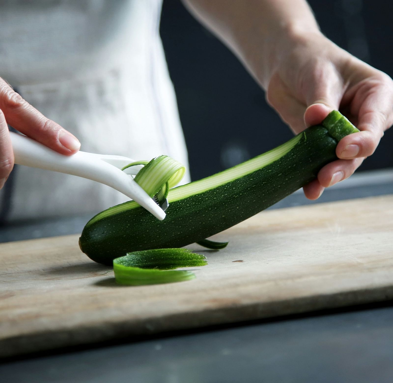 a hand thinly slicing the cucumber