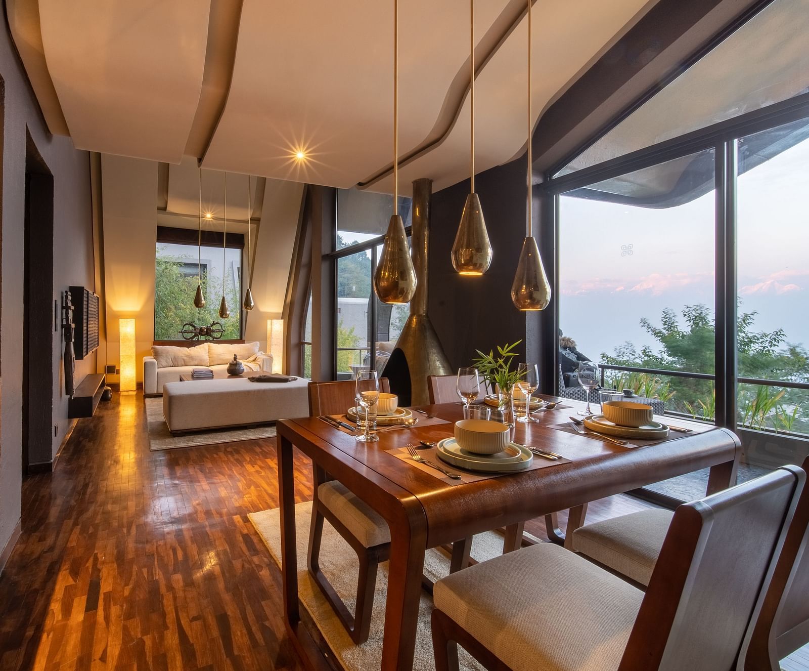 Open-plan dining and living area with elegant decor, large windows, and warm lighting.