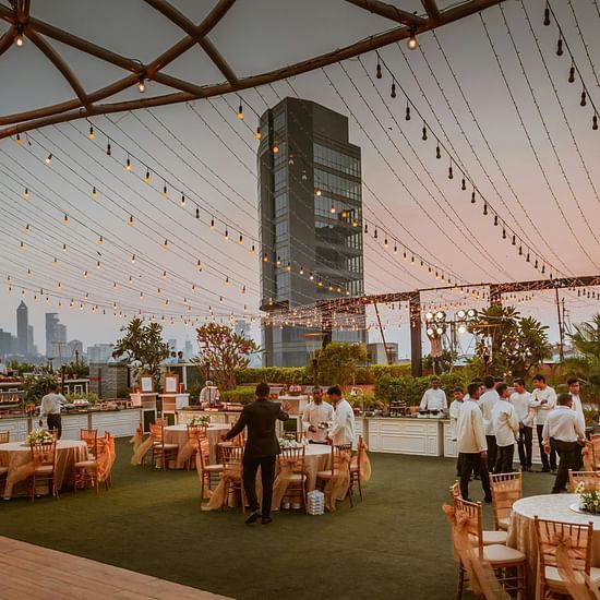 An outdoor event space on a rooftop or terrace, set with tables and chairs for dining.