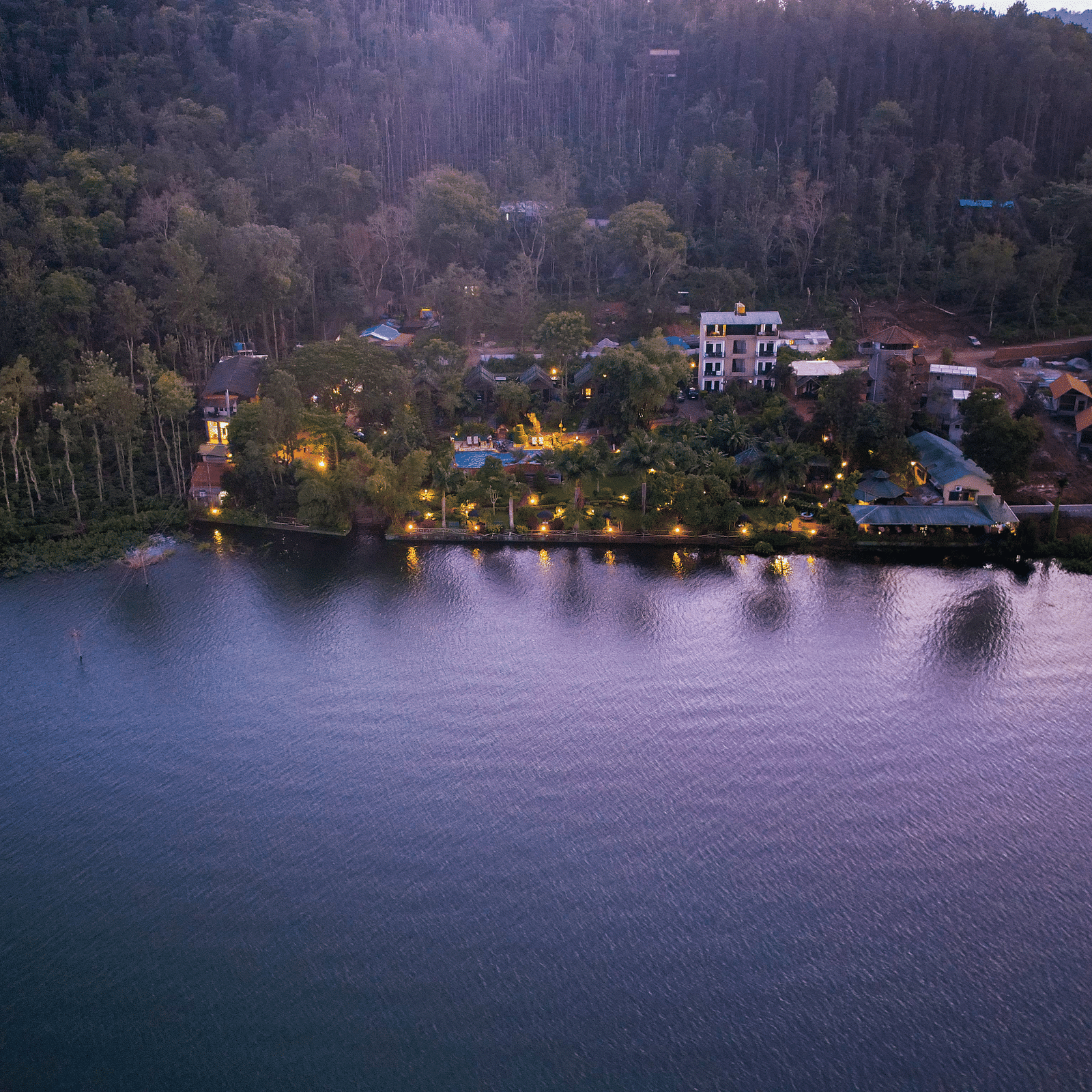 Aerial view of Coorg Jungle Camp Backwater Resort, Kushalnagar with a waterbody in front.