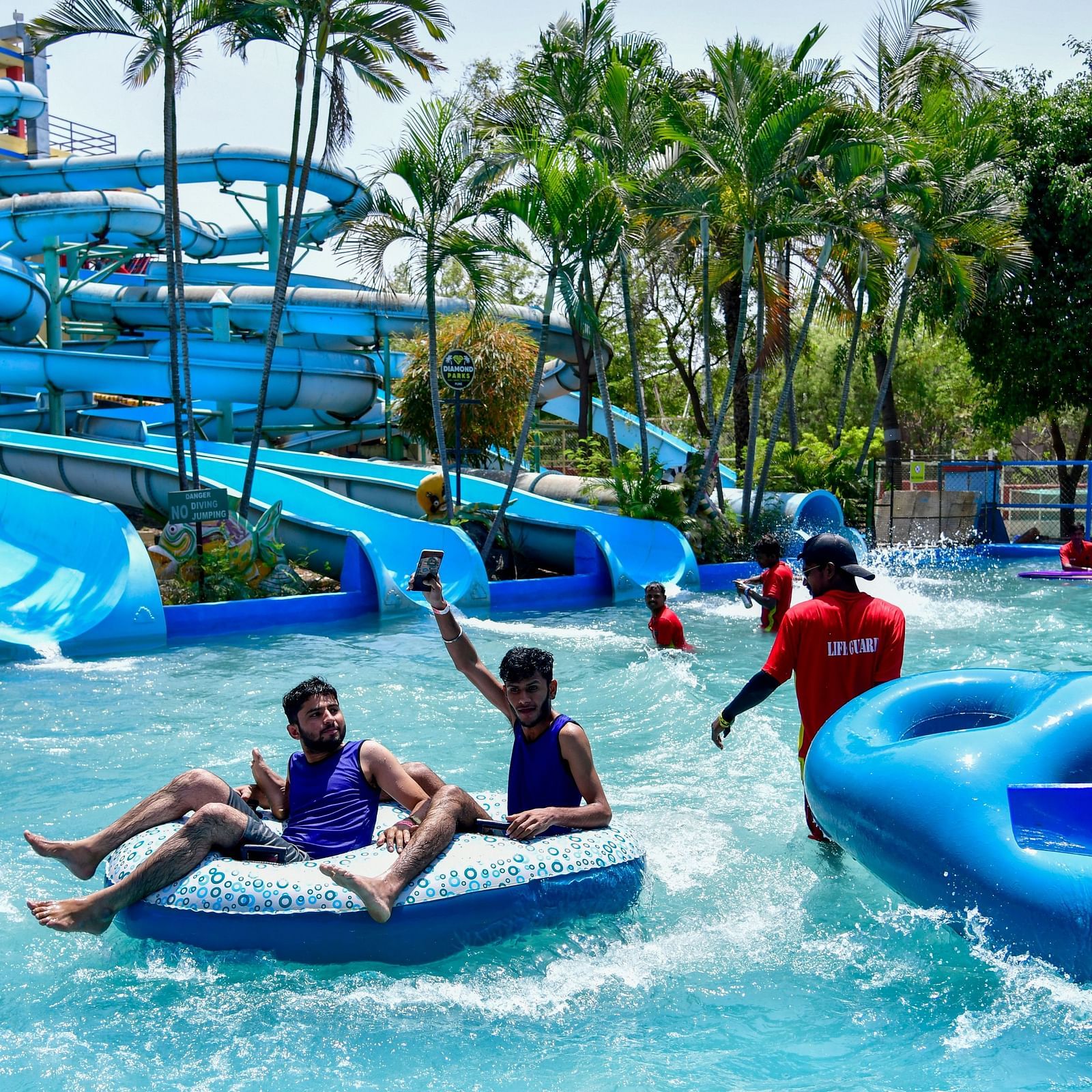 Visitors enjoying a lazy river ride with large blue tubes at a water park | Diamond Parks, Pune 