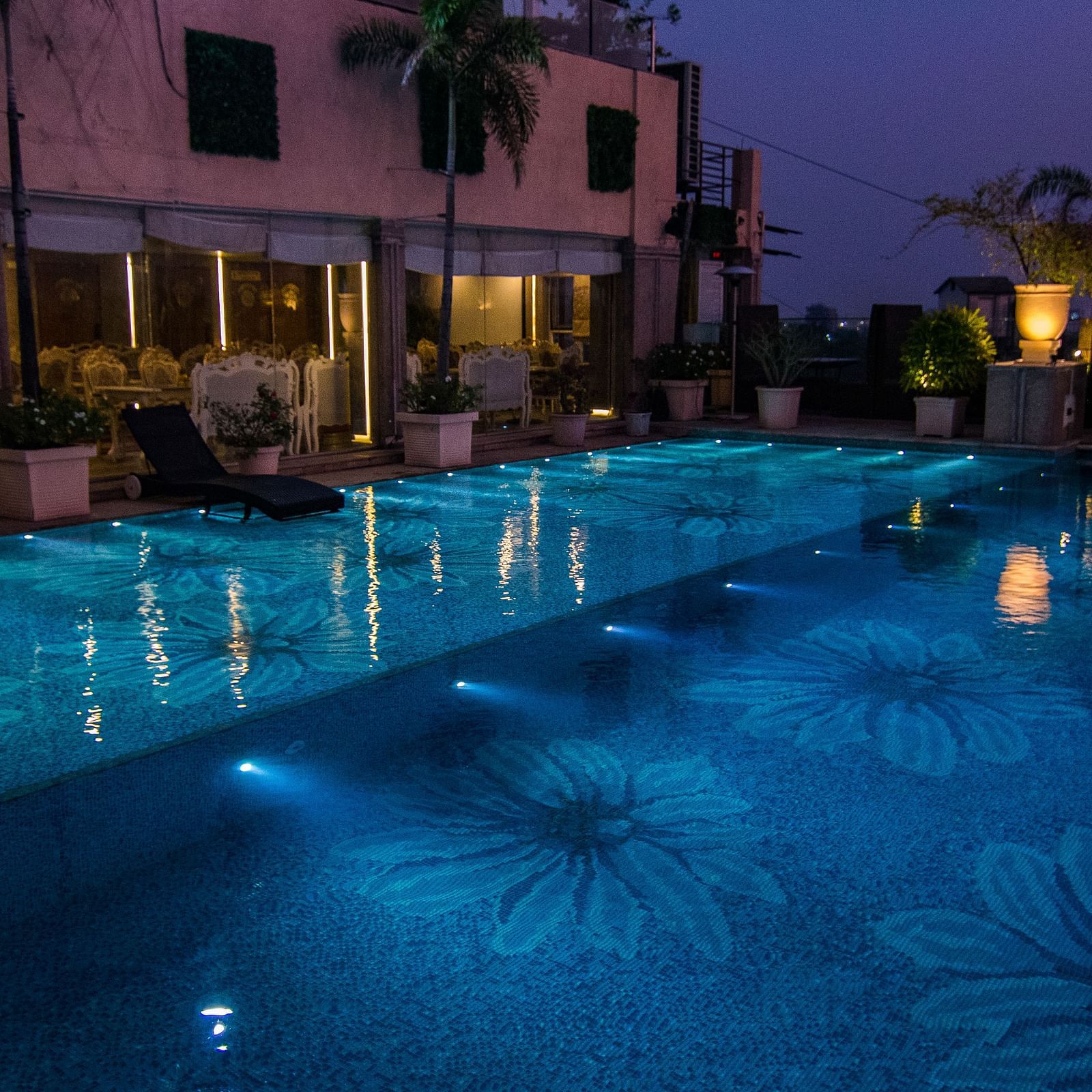 View of the swimming pool at night surrounded by lights at Hotel Ashok Nagpur.