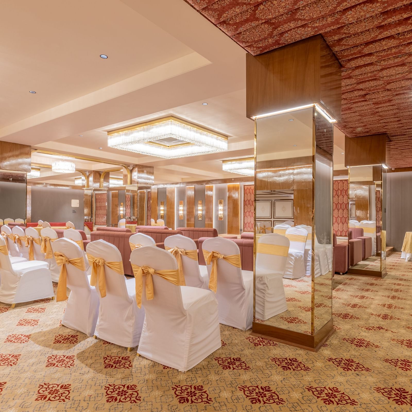 Banquet seating with white-covered chairs tied in gold sashes arranged around a stage setup at Hotel Highway King, Jaipur.