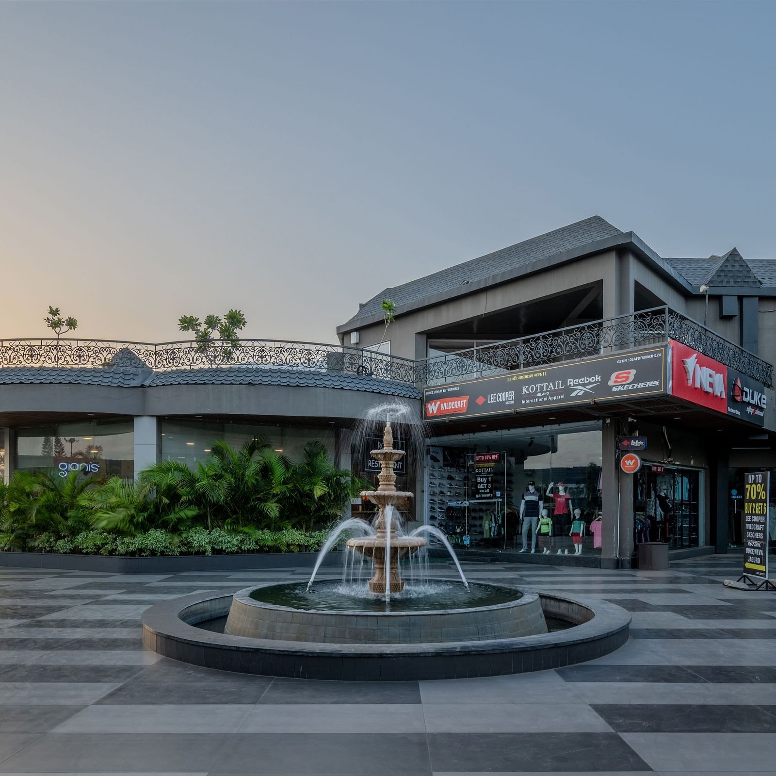 A wide exterior shot of Hotel Highway King Shahpura, featuring a fountain and pathways.