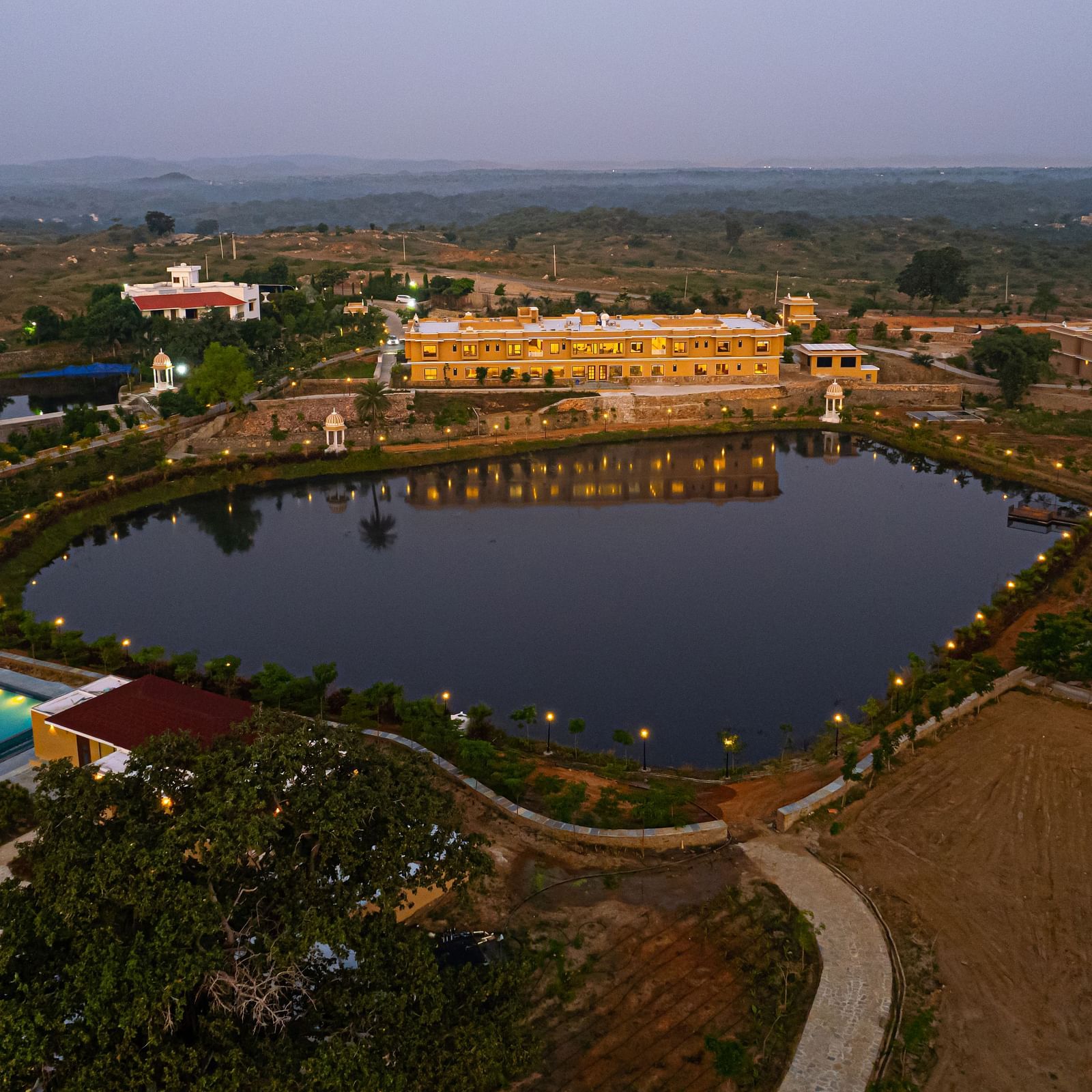 An aerial shot of our property seen during twilight with a water body in front of it - Rajbagh Wellness, Udaipur