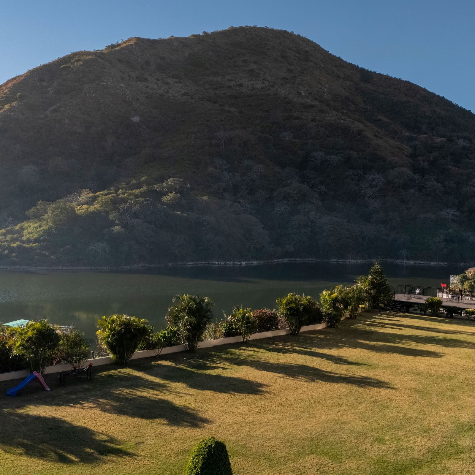 Mountain with a winding road, trees, and water visible, sunny day - Via Lakhela Resort & Spa