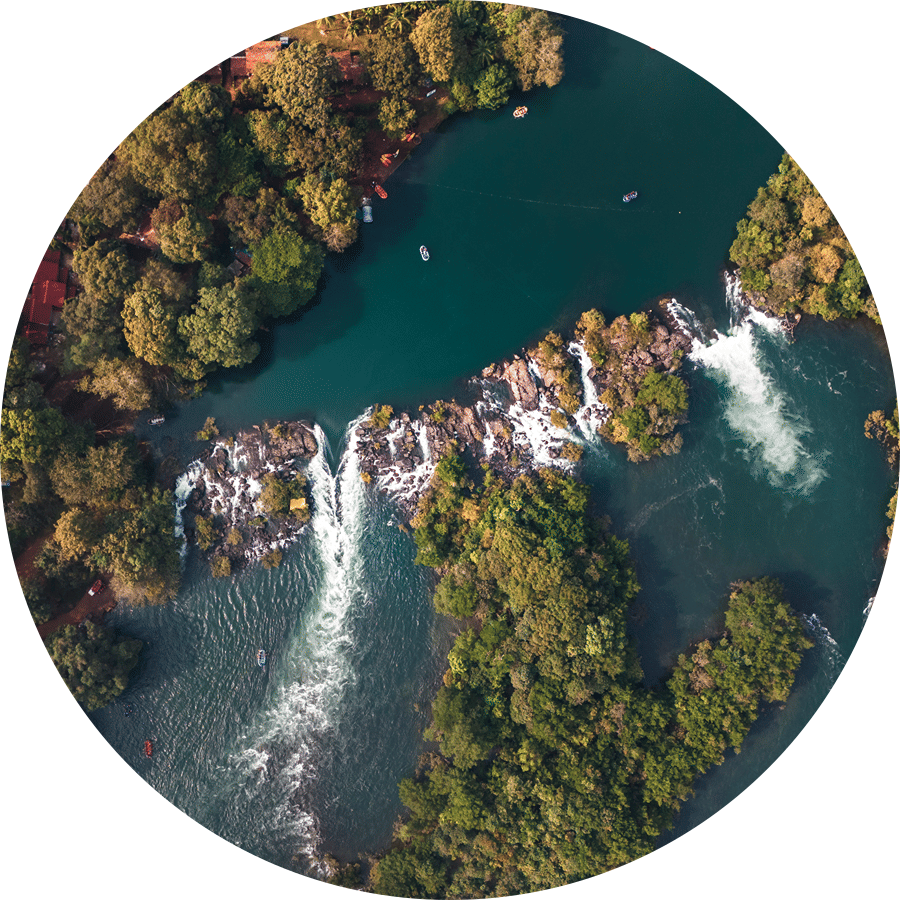 Aerial view of a wide waterfall cascading through dense forest surrounding a river