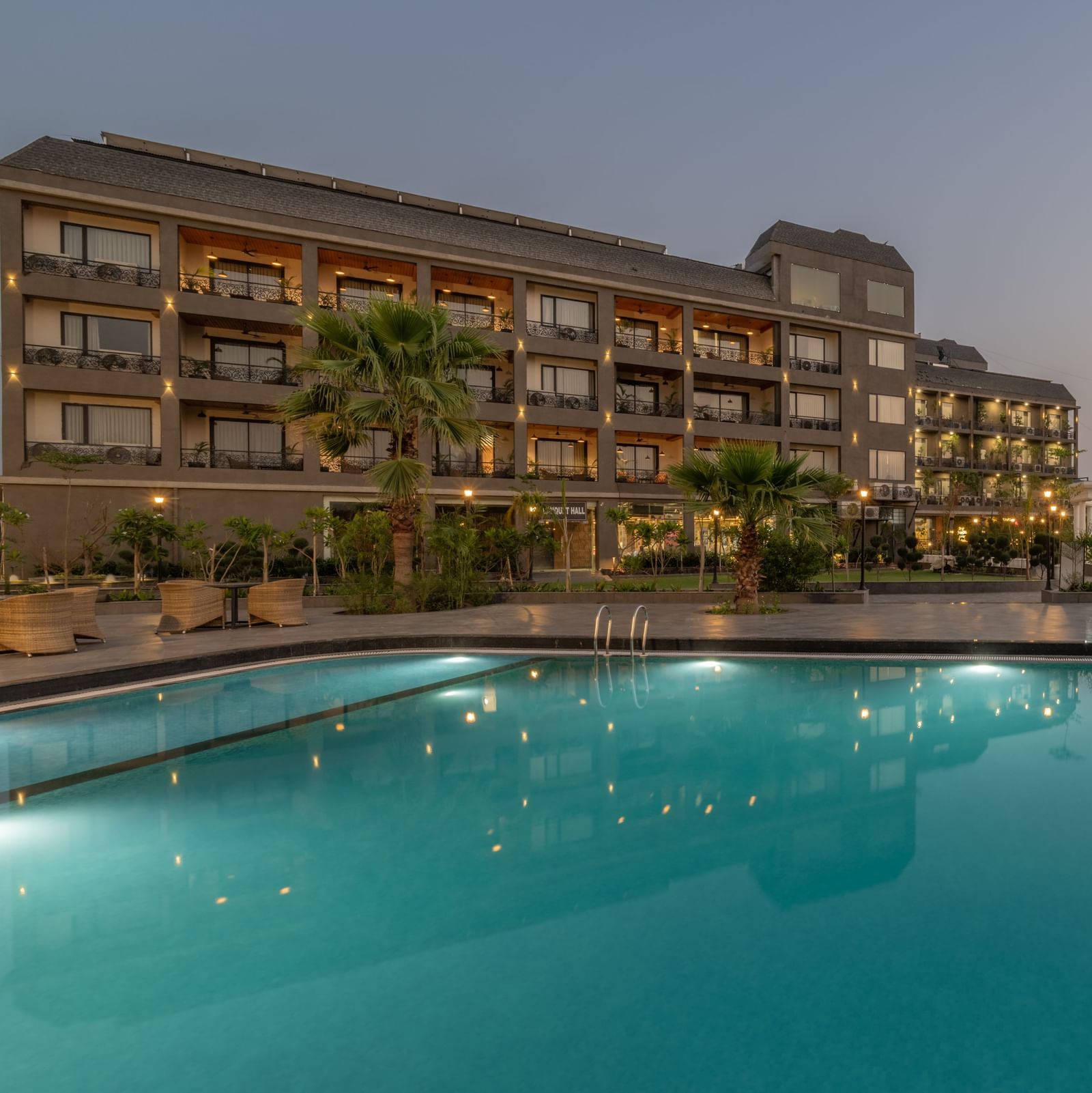 Swimming pool area at Hotel Highway King, Bagru, with loungers, landscaped surroundings, and the main building in view.