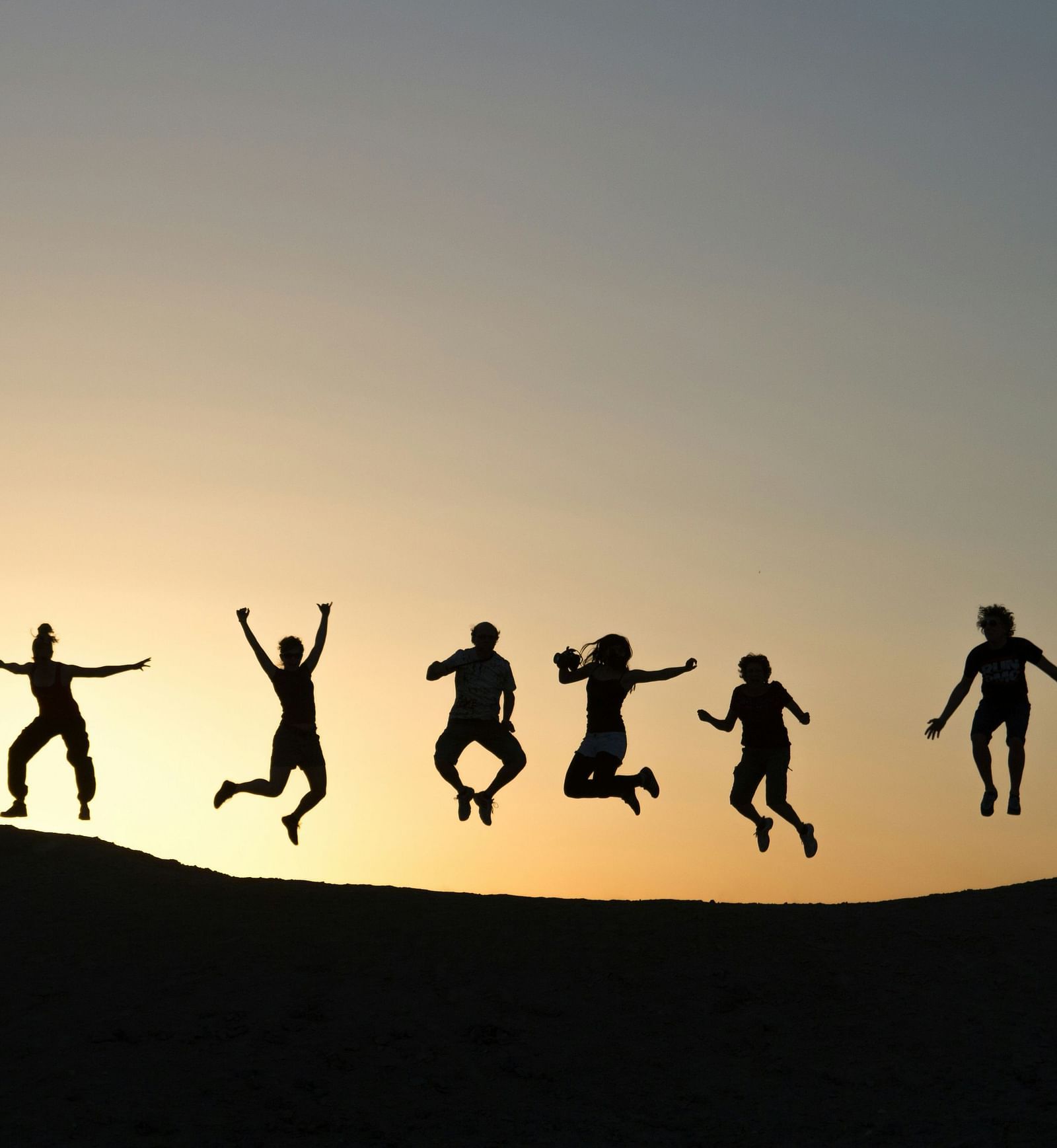 A group of people jumping and posing for a picture with sun setting in the background |  Mango Hill, Pondicherry