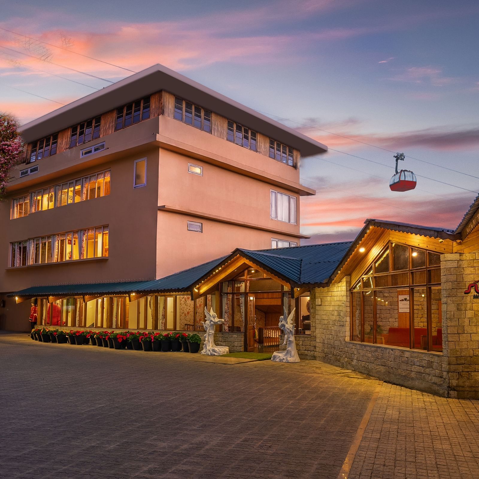 Pathway to Summit Namnang Courtyard & Spa, Gangtok, surrounded by vibrant plants with a stunning sunset in the background