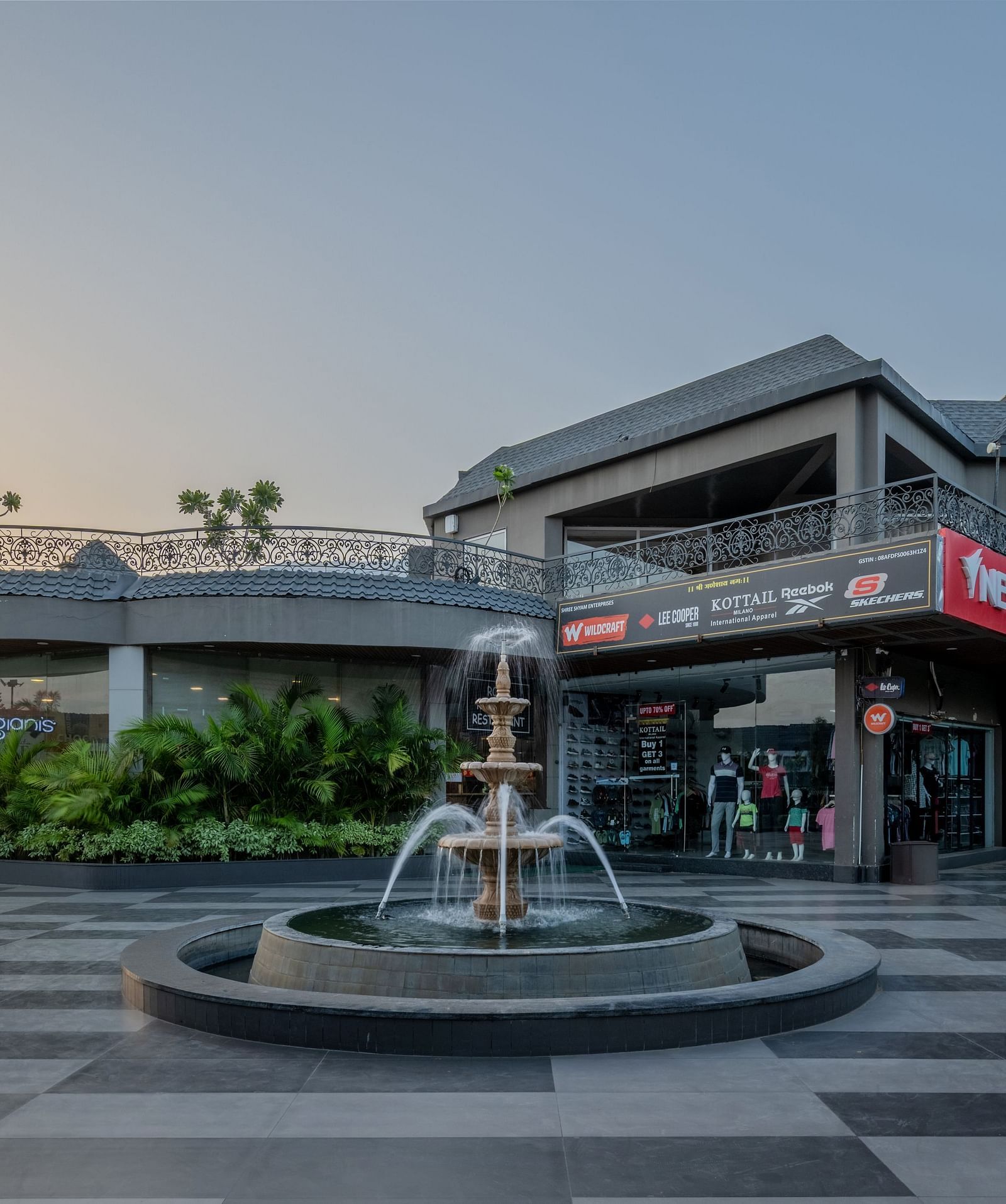 A wide exterior shot of Hotel Highway King Shahpura, featuring a fountain and pathways.