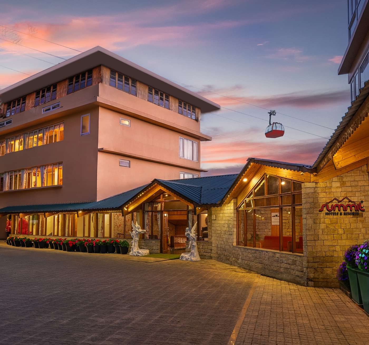 Pathway to Summit Namnang Courtyard & Spa, Gangtok, surrounded by vibrant plants with a stunning sunset in the background