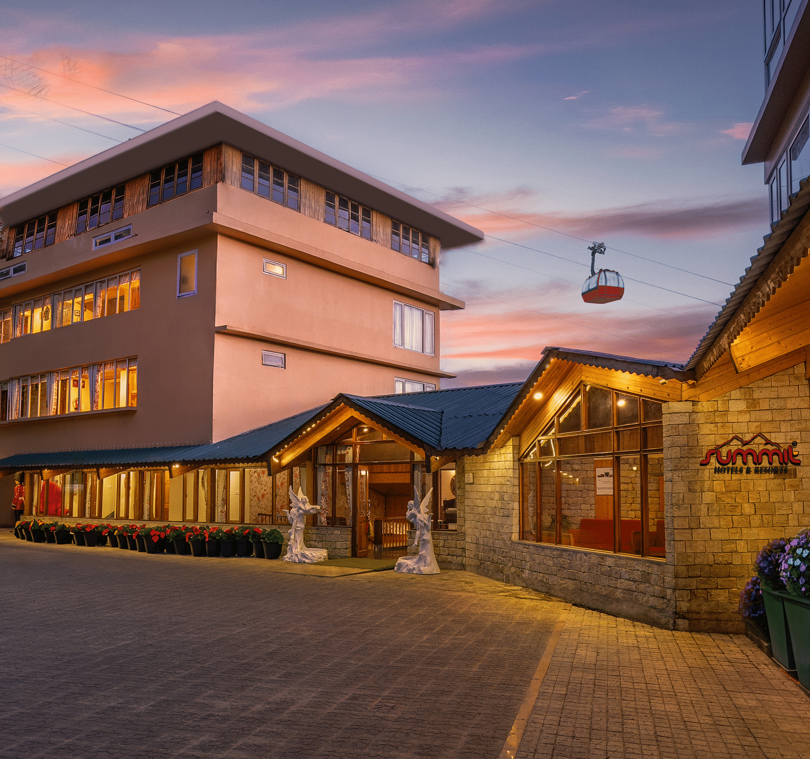 Pathway to Summit Namnang Courtyard & Spa, Gangtok, surrounded by vibrant plants with a stunning sunset in the background