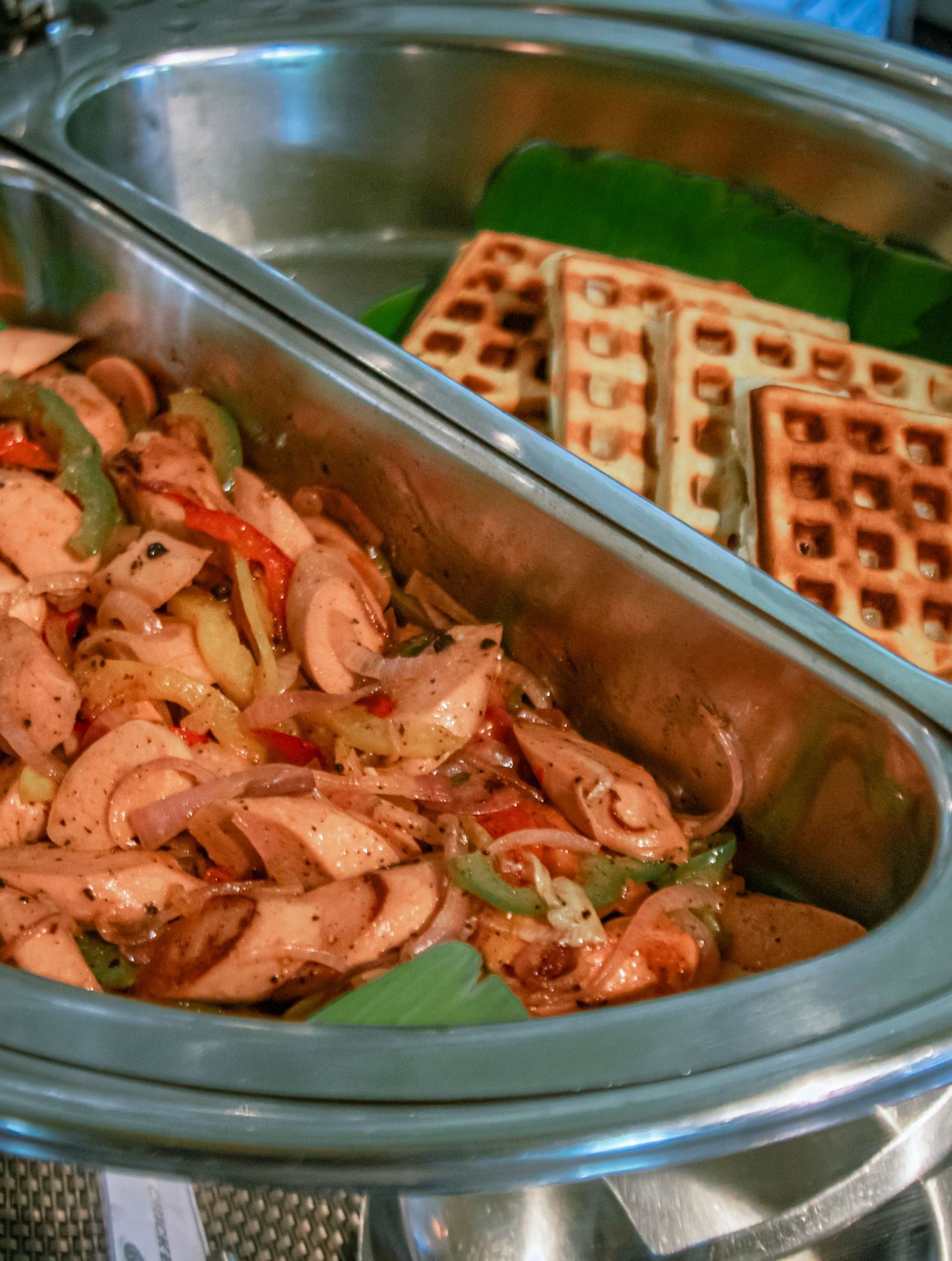Chafing dish with fried bacon and  waffles on a buffet counter at Fireflies Resorts, Kabini.