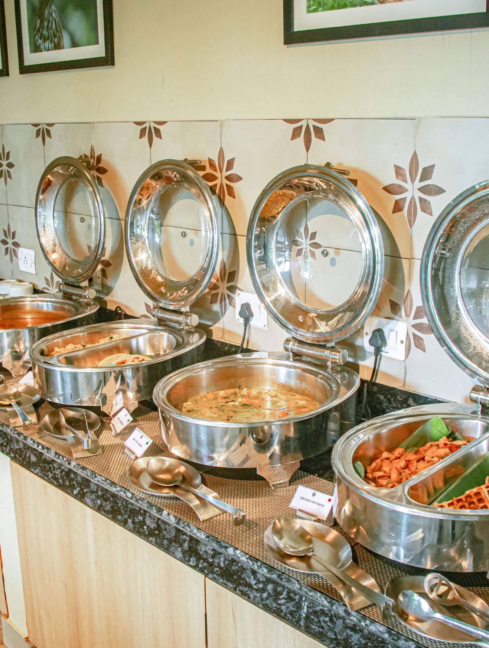 Indoor buffet counter with a row of dishes arranged along a granite-topped wooden counter at Fireflies Resorts, Kabini.