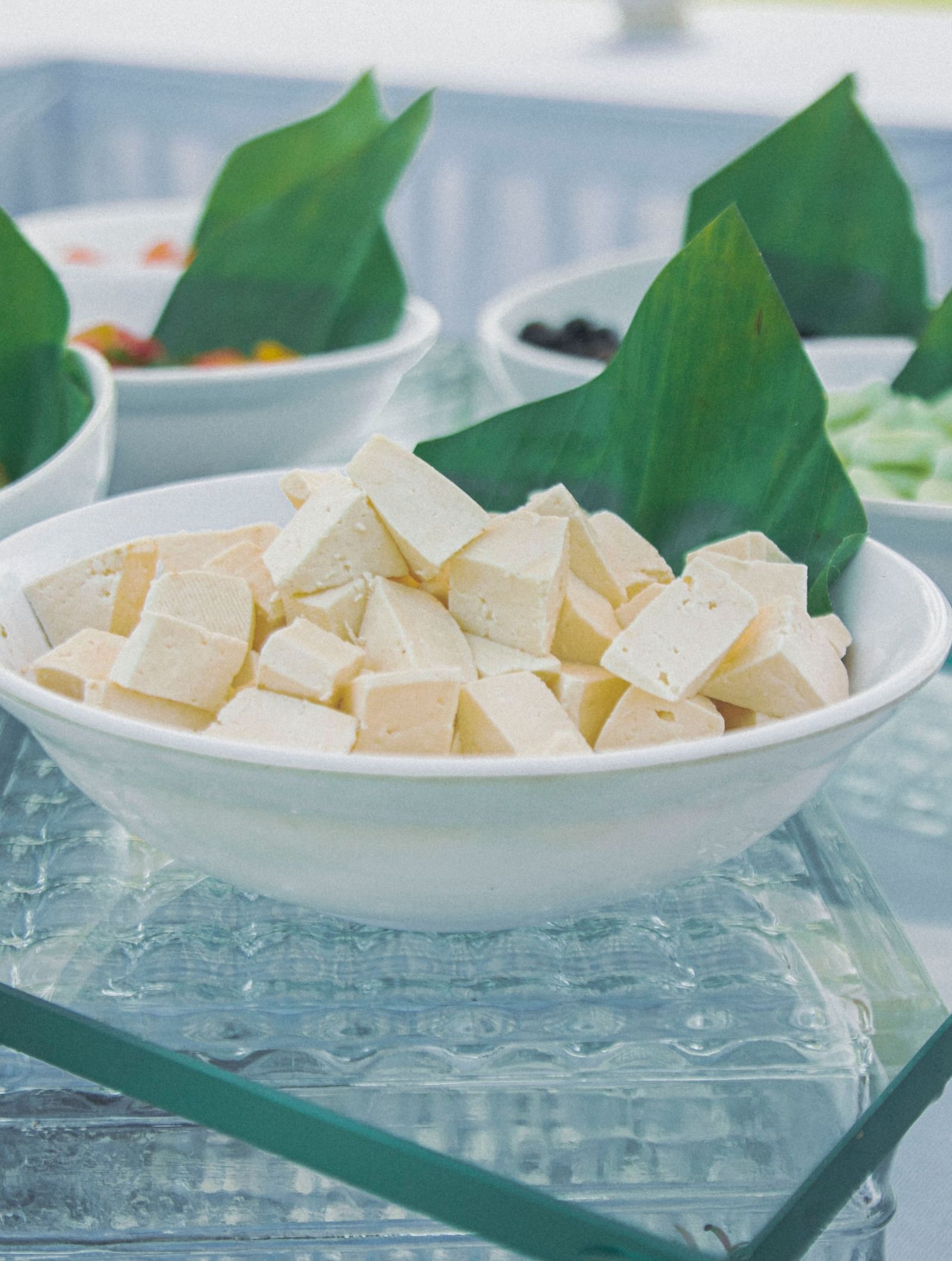 Bowl of diced cheese beside bowls of olives and greens placed on a glass buffet counter at Fireflies Resorts, Kabini.