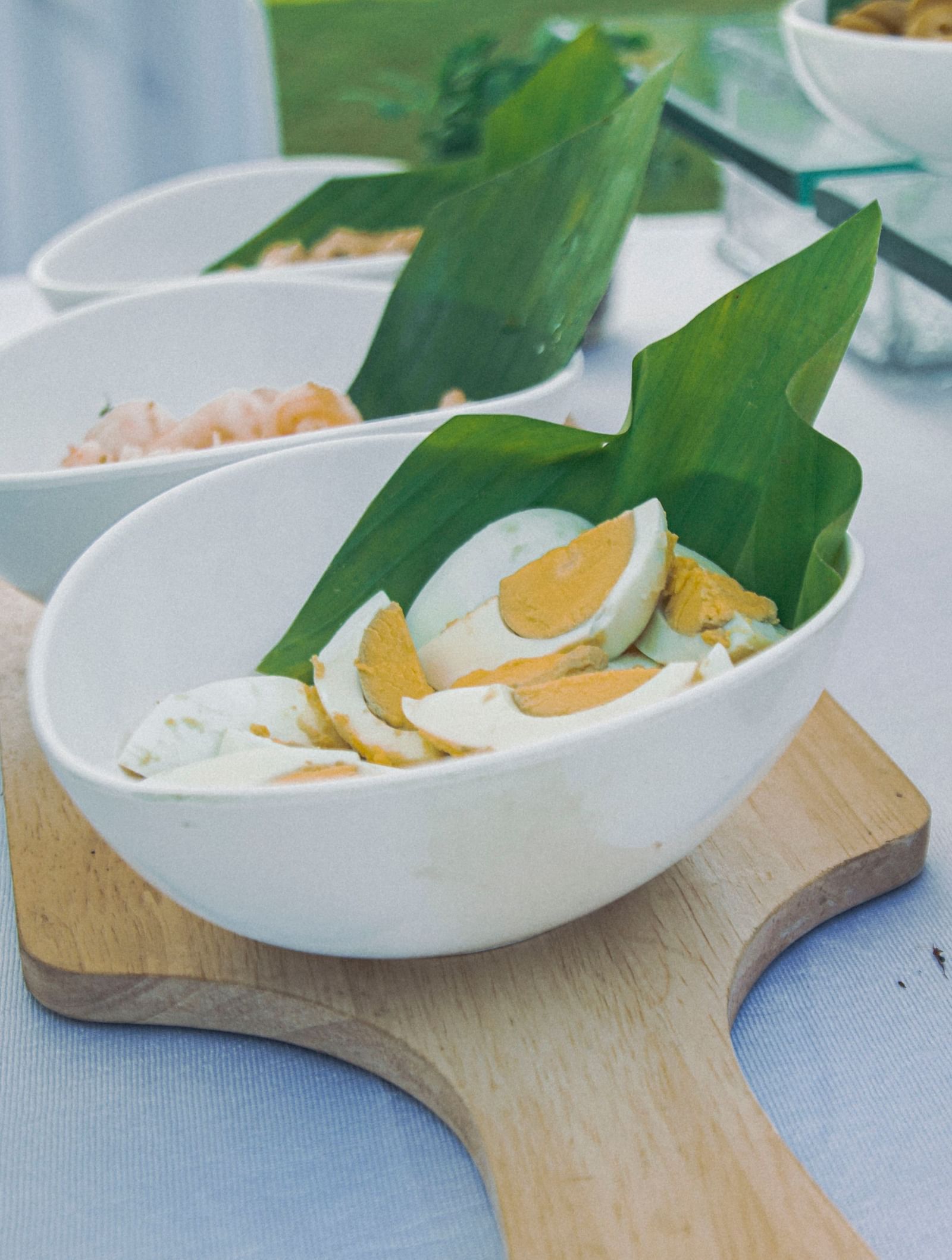Bowl of sliced eggs and greens placed on a wooden tray beside other dishes at Fireflies Resorts, Kabini.