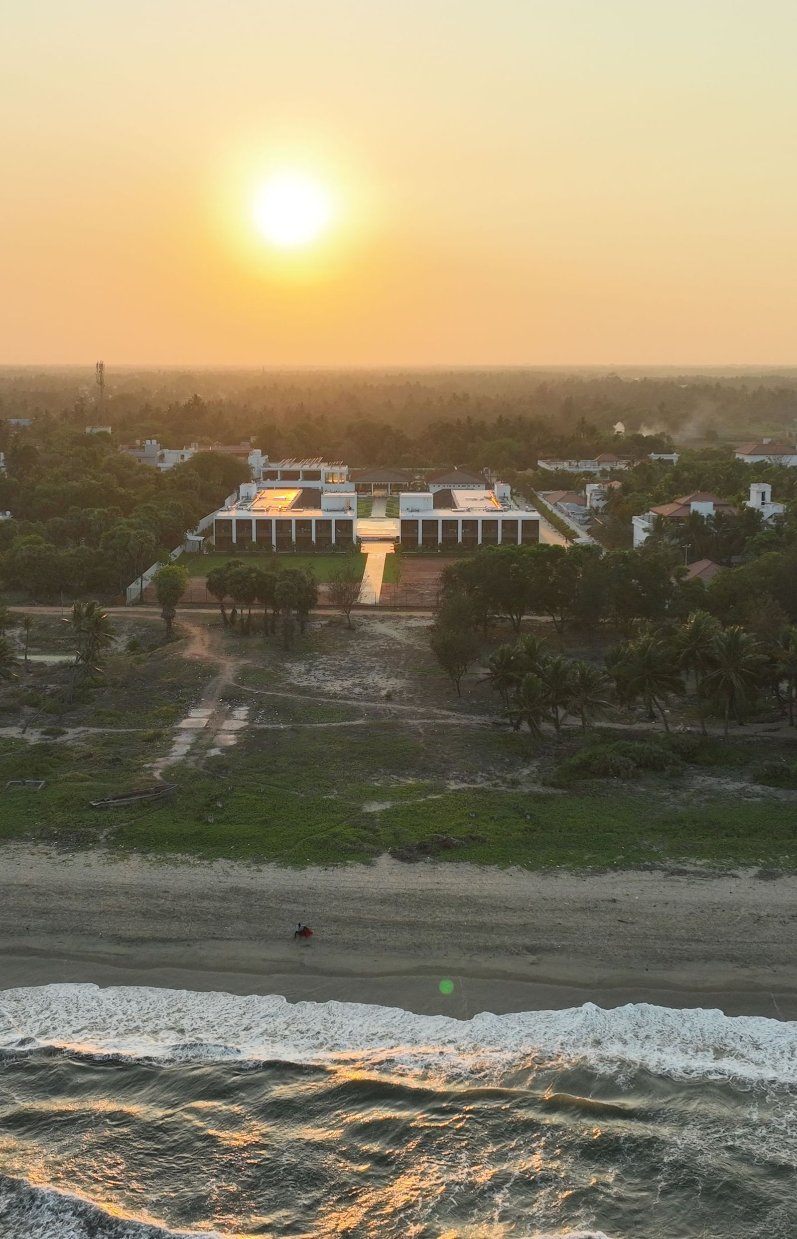 Facade image of the resort with the ocean waves crashing the beach shoreline at The Shore Trishvam, Pondicherry.