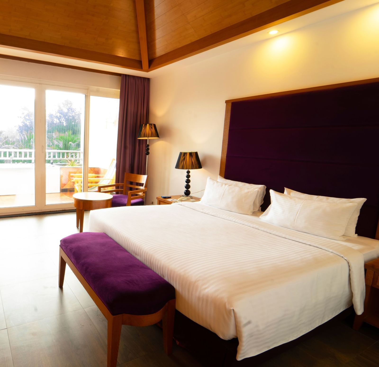 A luxurious hotel bedroom with a large bed, purple accents, and a balcony - Ocean Spray, Pondicherry 