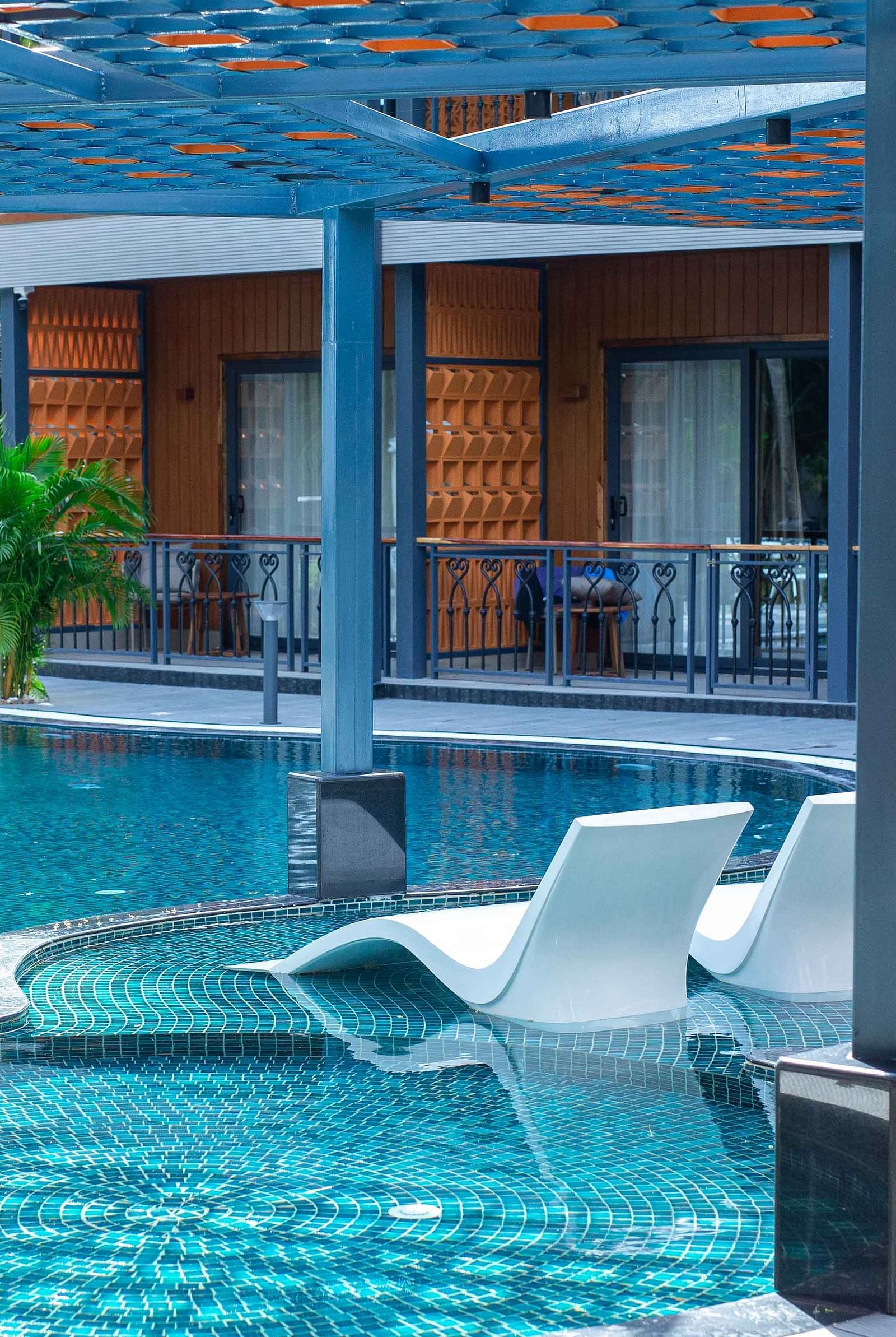  A close-up view of a modern resort pool area with lounge chairs partially submerged in the water. The design offers a serene and luxurious space for guests - Coral Reef Resort & Spa, Havelock