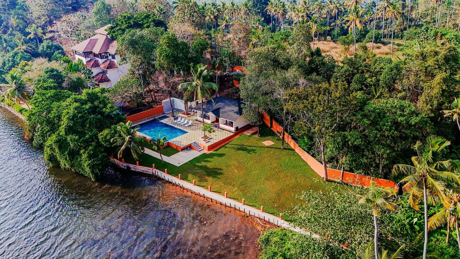 Villa nestled amongst lush greenery overlooking a scenic waterway - kerala resort photos