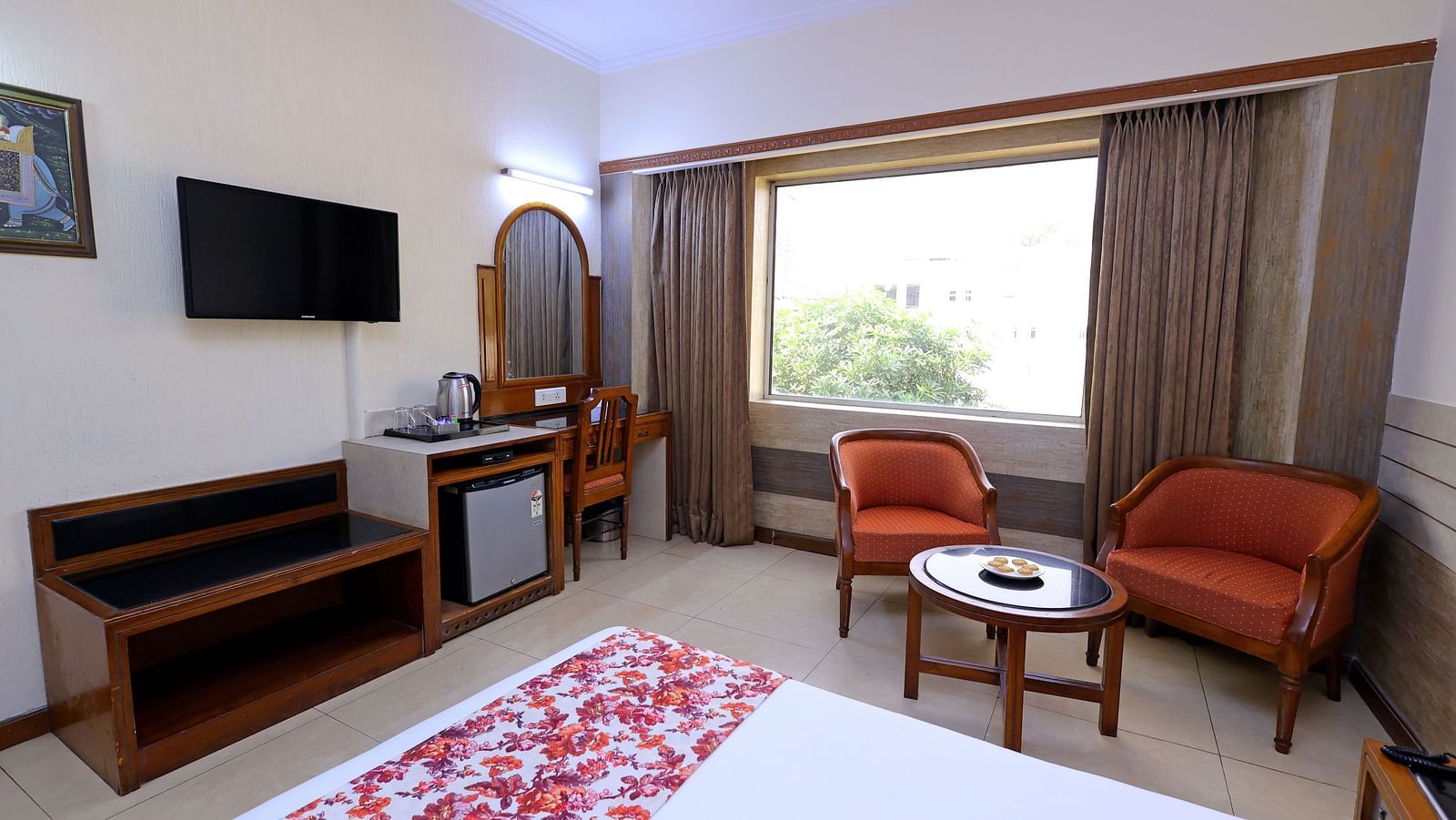 Side view Executive room of Hotel Amar with a  bed table, TV, a big window and chairs