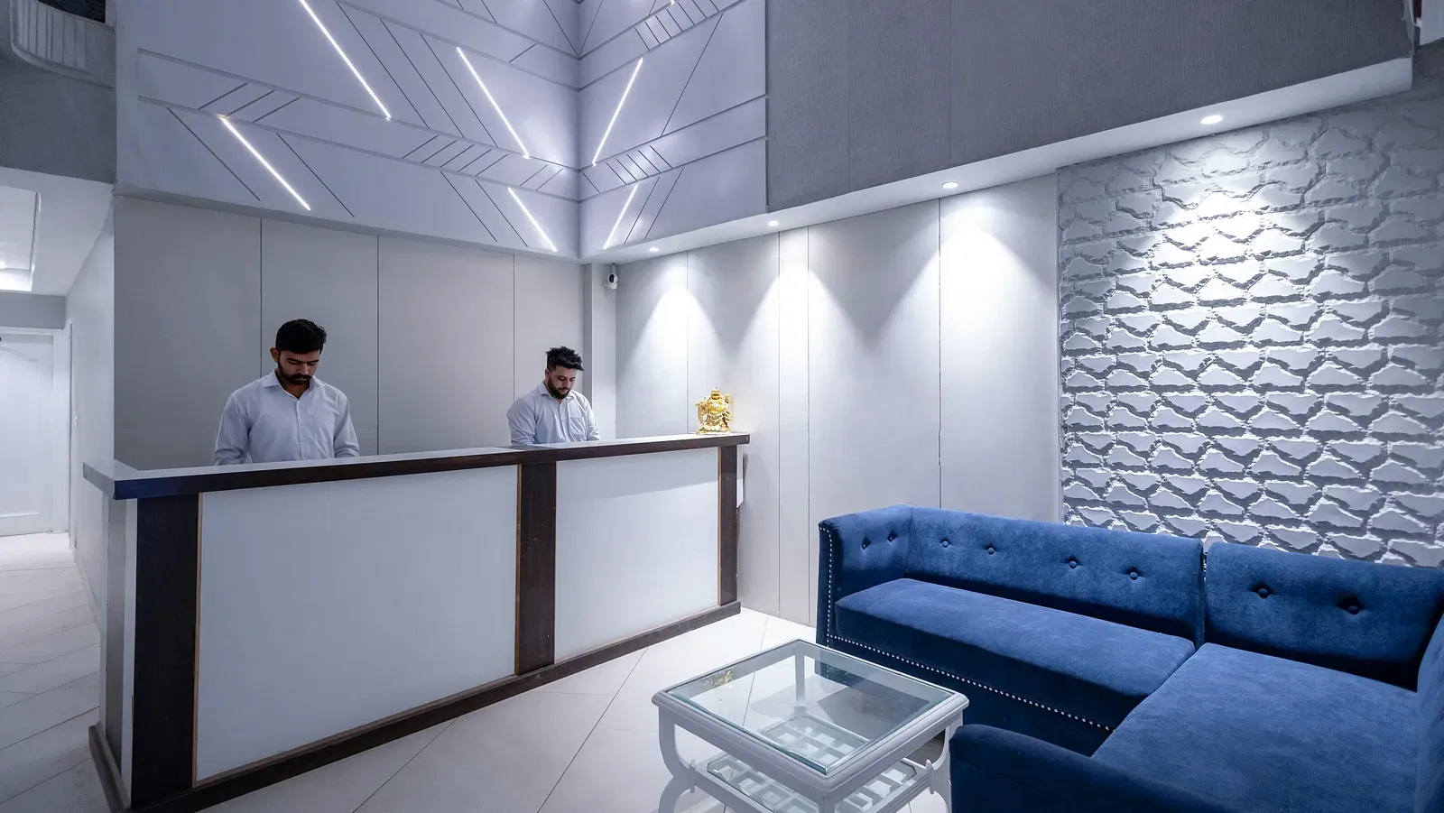 Hotel Downtown17 lobby in Chandigarh featuring a blue couch with receptionists standing near the desk.