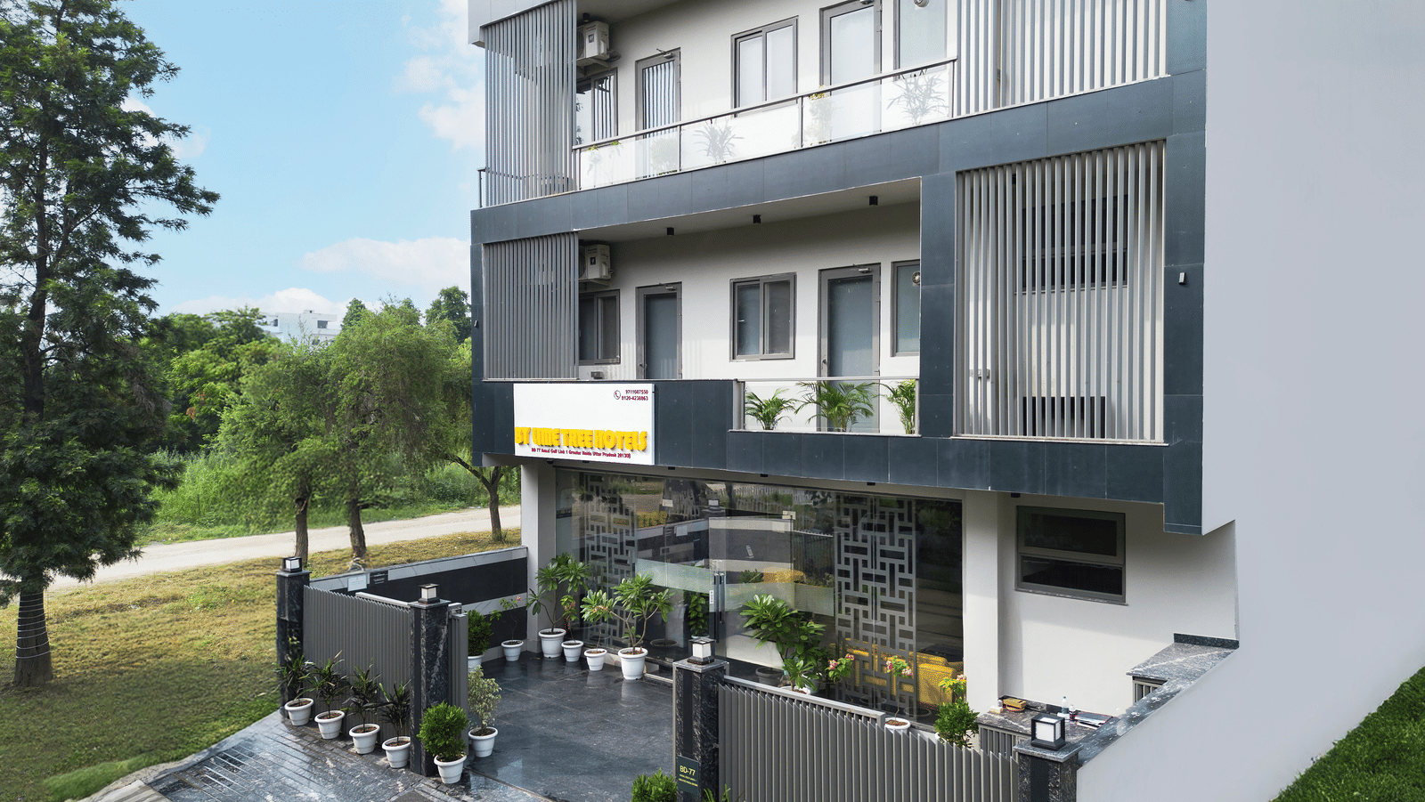 Entrance of Lime Tree Hotels & Service Apartment Private Limited featuring a canopy, surrounding greenery, and a paved driveway.