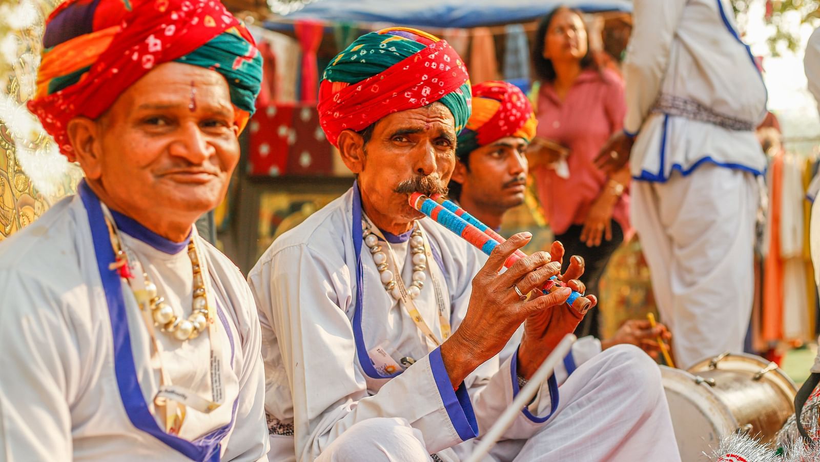 A traditional setting with three men in traditional Rajasthani attire playing musical instrument
