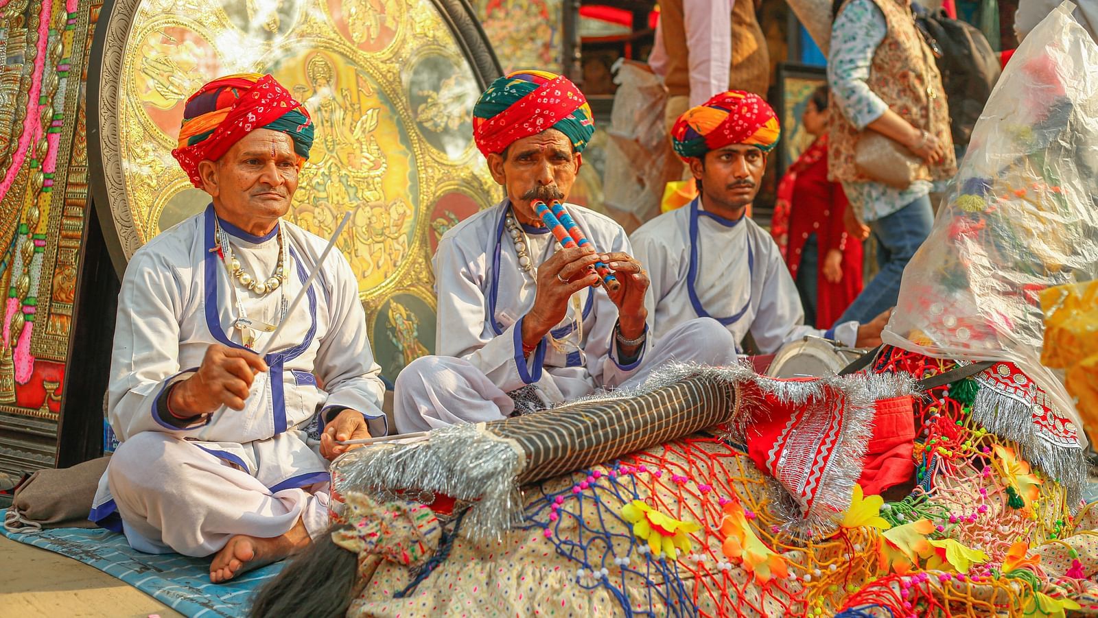 A traditional setting with three men in traditional Rajasthani attire playing musical instrument