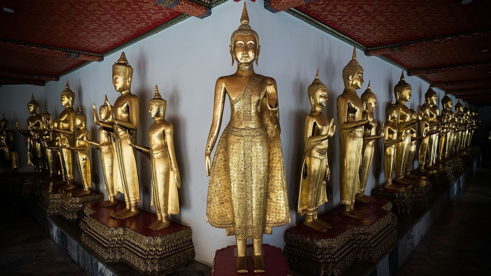 Mant statues of Buddha, gold plated kept next to the wall inside Wat Pho.