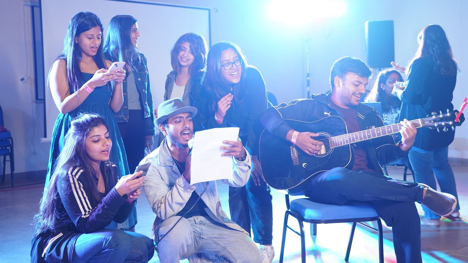 A group of people at Ravishing Retreat singing and jamming while another person is sitting on the chair and playing guitar