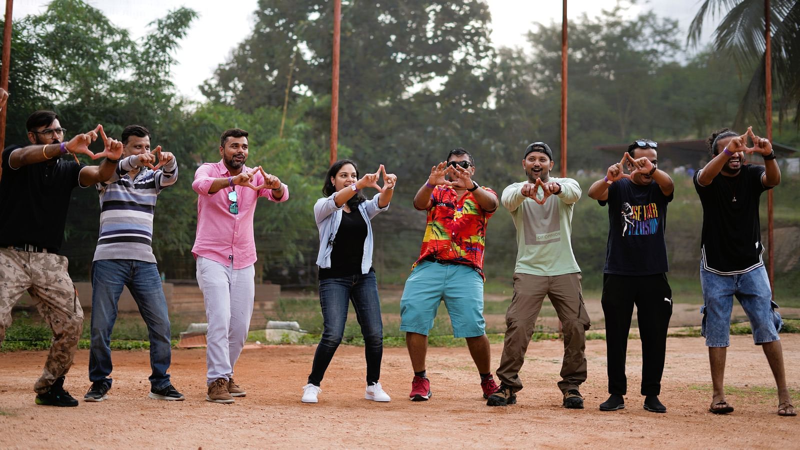 A group of people at Ravishing Retreat doing hand sign while posing for a picture and smiling