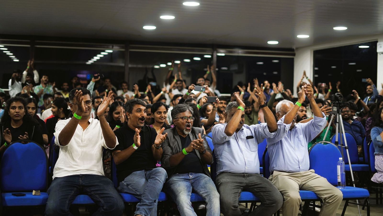 People seated in an auditorium at Ravishing Retreat and raising their hands to clap
