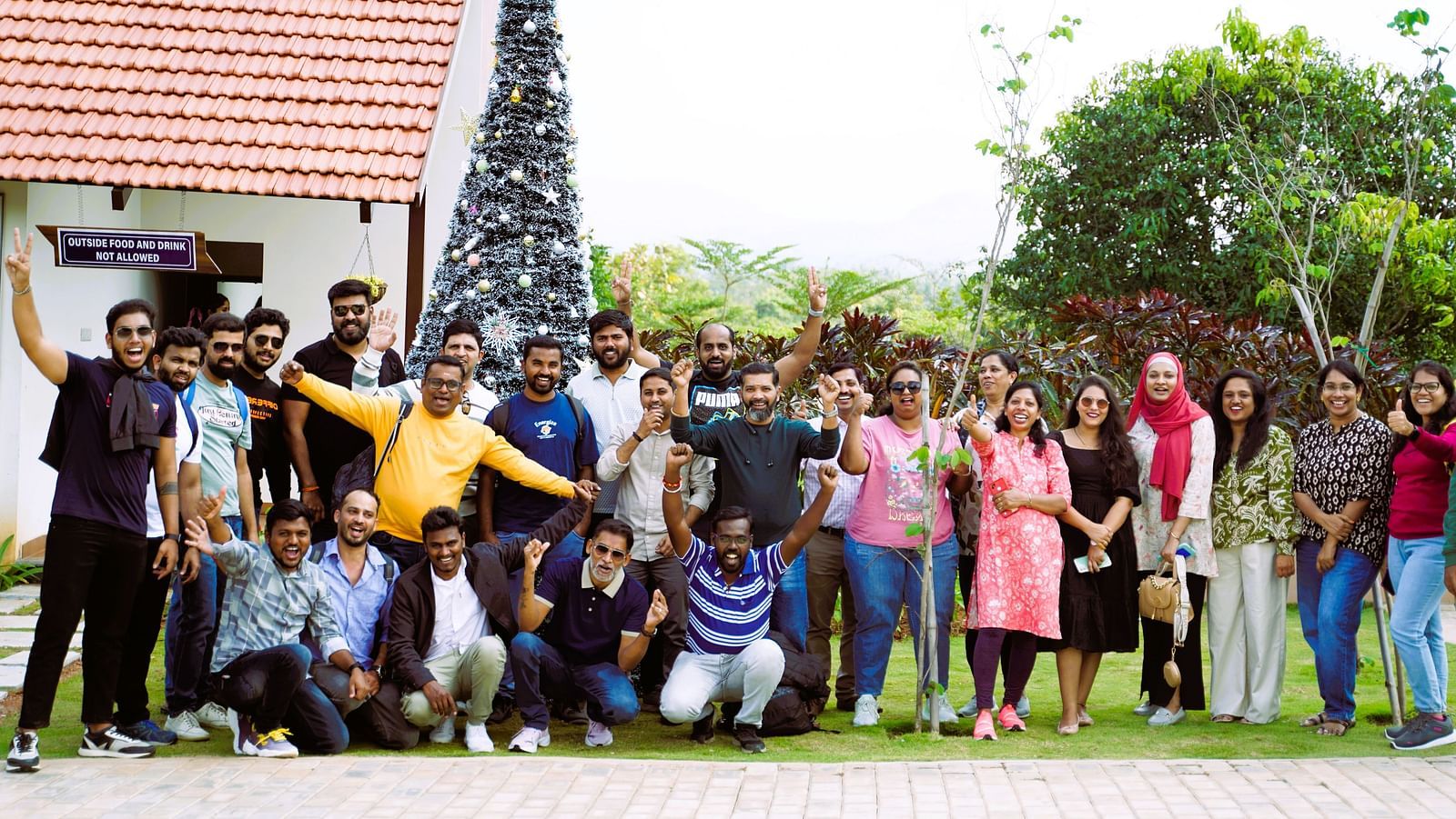 A group of people at Ravishing Retreat standing in front of a giant Christmas tree and posing for a photo
