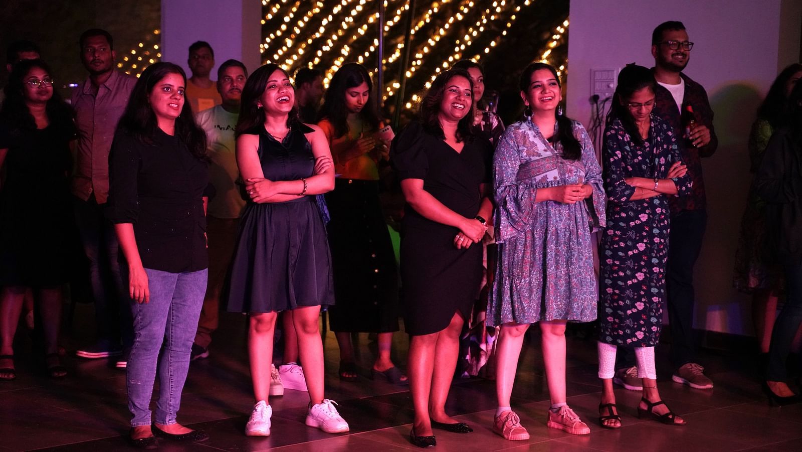 A group of ladies standing and smiling under vibrant lighting at Ravishing Retreat 