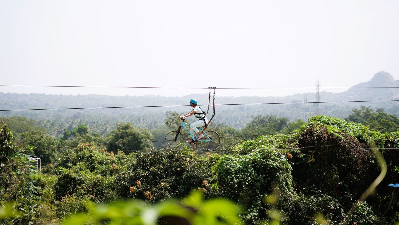 Image of a person in the air enjoying zip-cycling at Ravishing Retreat on a sunny day amid greenery
