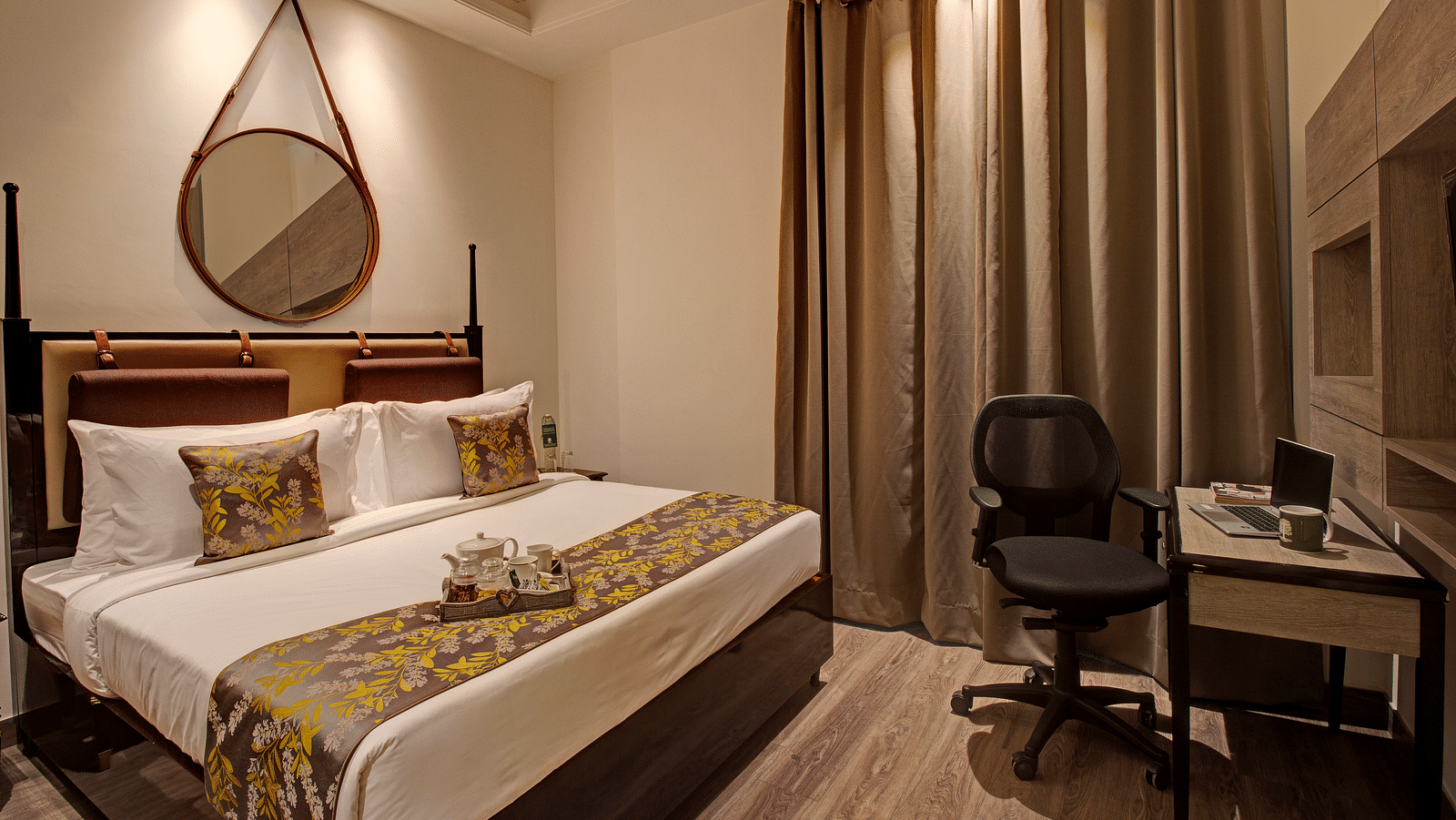 A double bed in the Presidential Suite with a table opposite the bed at Rhythm Gurugram