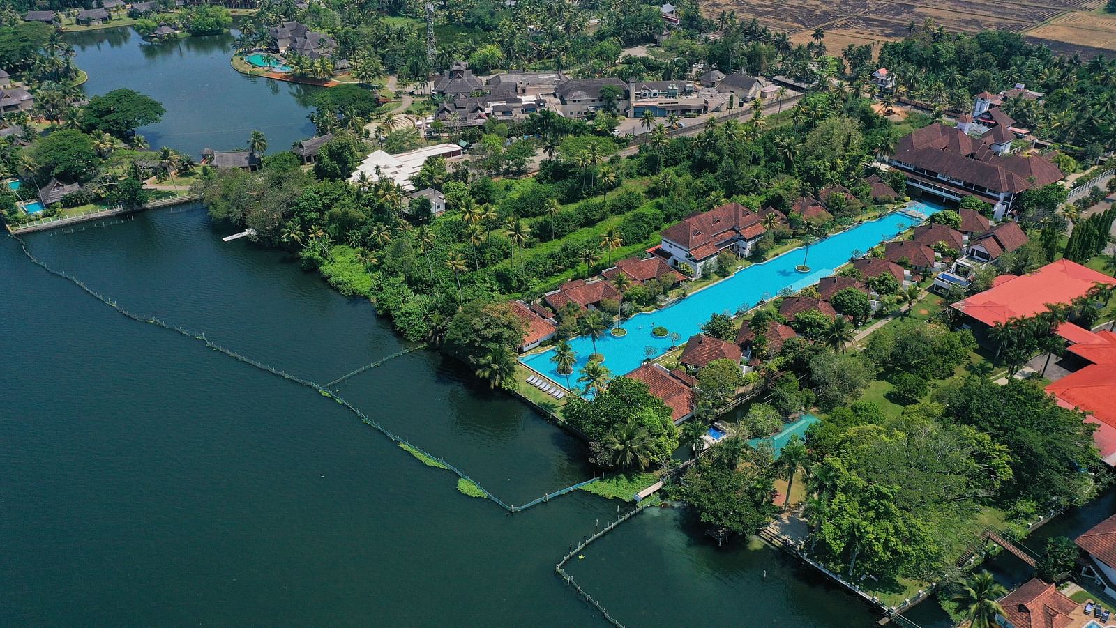 an image of Bird's-eye view of a Rhythm Kumarakom nestled by a lake, surrounded by rich greenery - Rhythm Kumarakom
